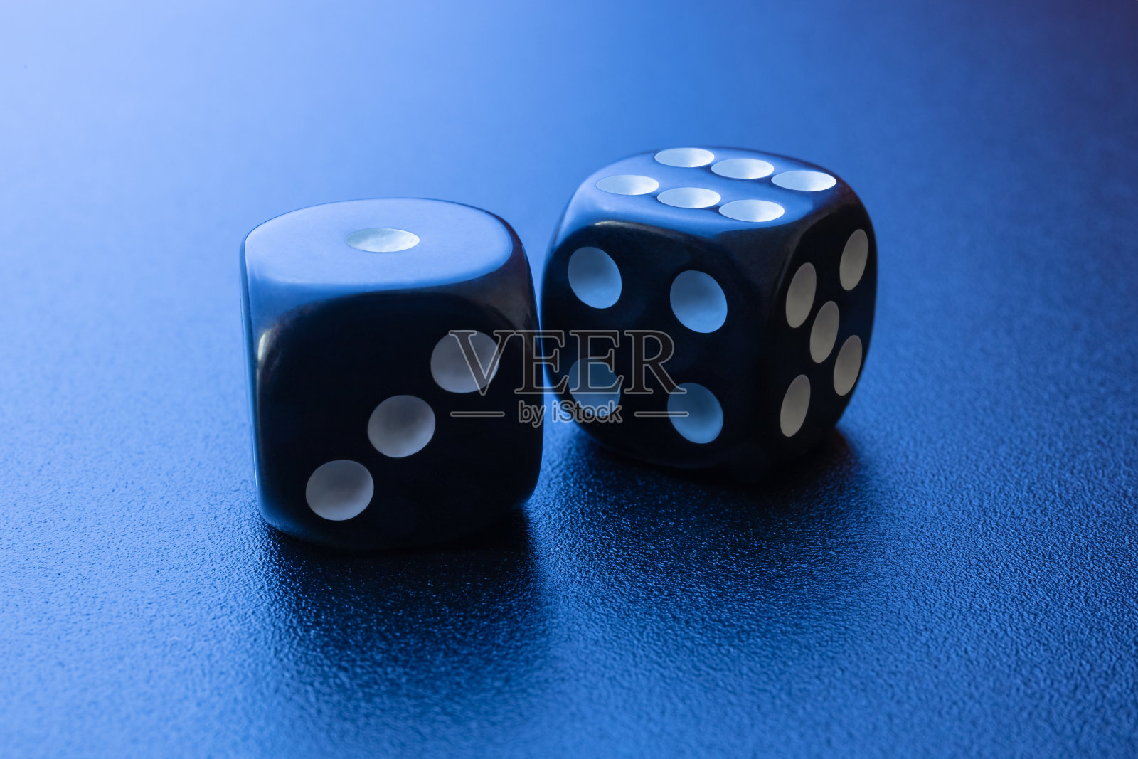 两个黑色骰子在黑色哑光背景与侧面蓝色照明。一个和6个。照片摄影图片