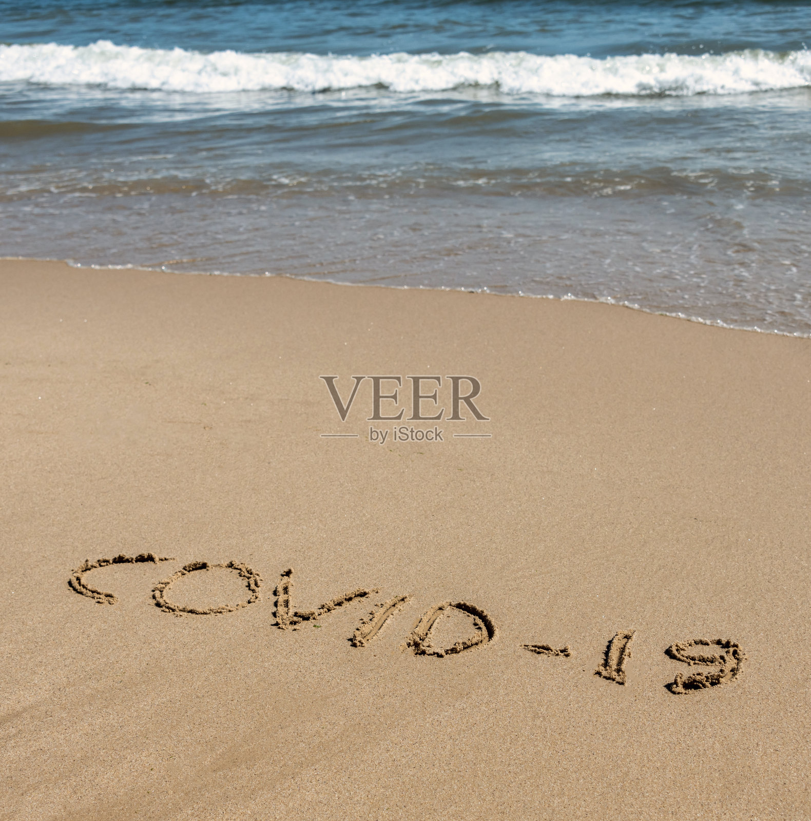 COVID-19写在沙滩上的沙子和大海照片摄影图片