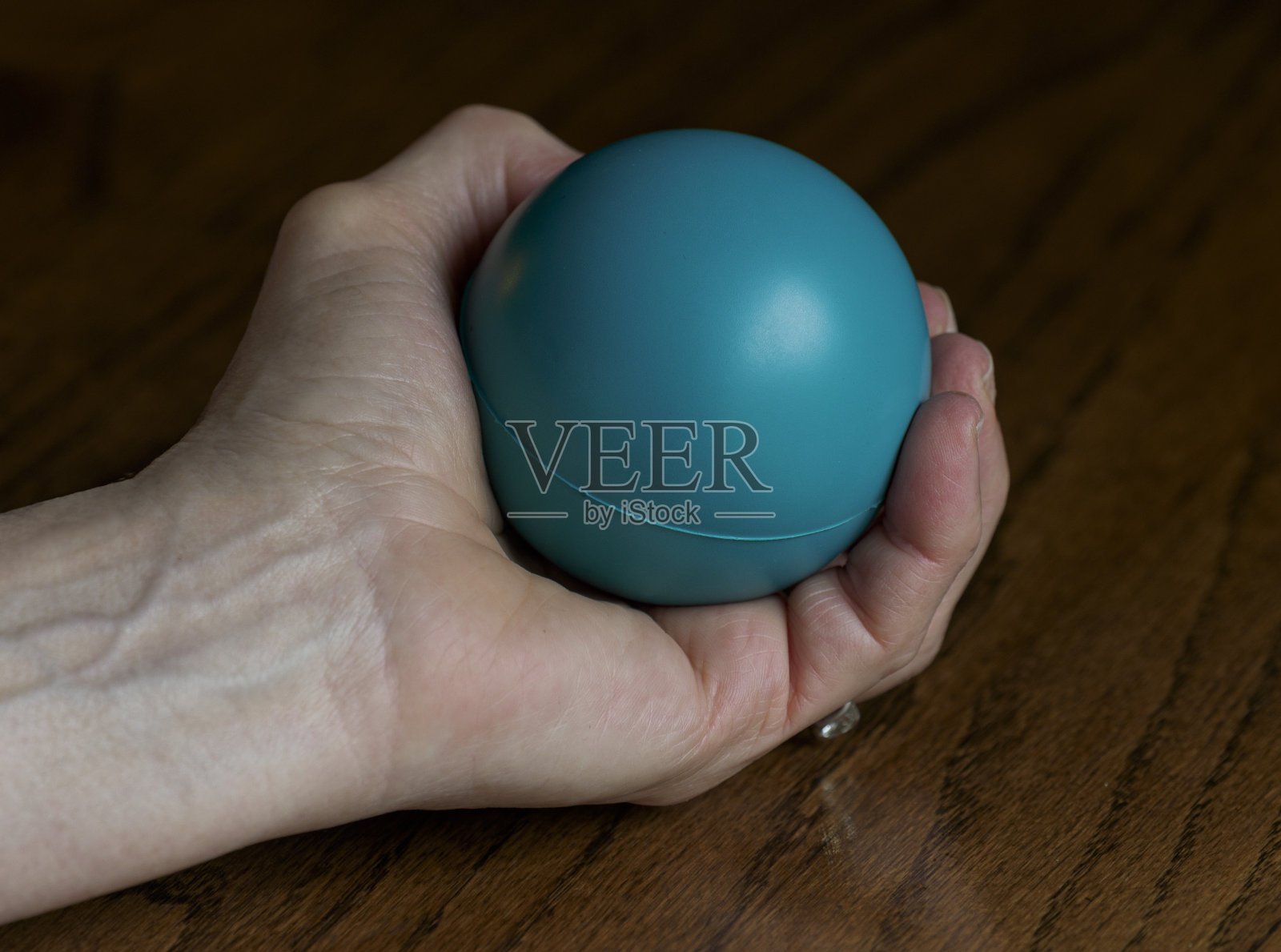 老女人用压力球在桌子上练习她的手照片摄影图片