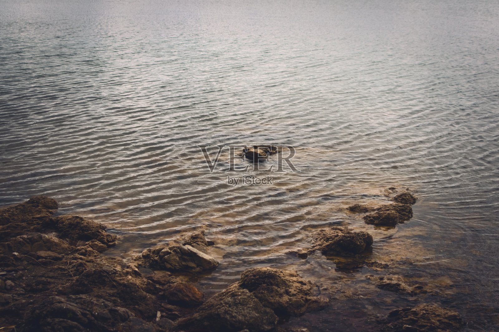 在一个黑暗多云的日子里,阿根廷圣路易斯市拉弗罗里达湖的岩石岸边。照片摄影图片