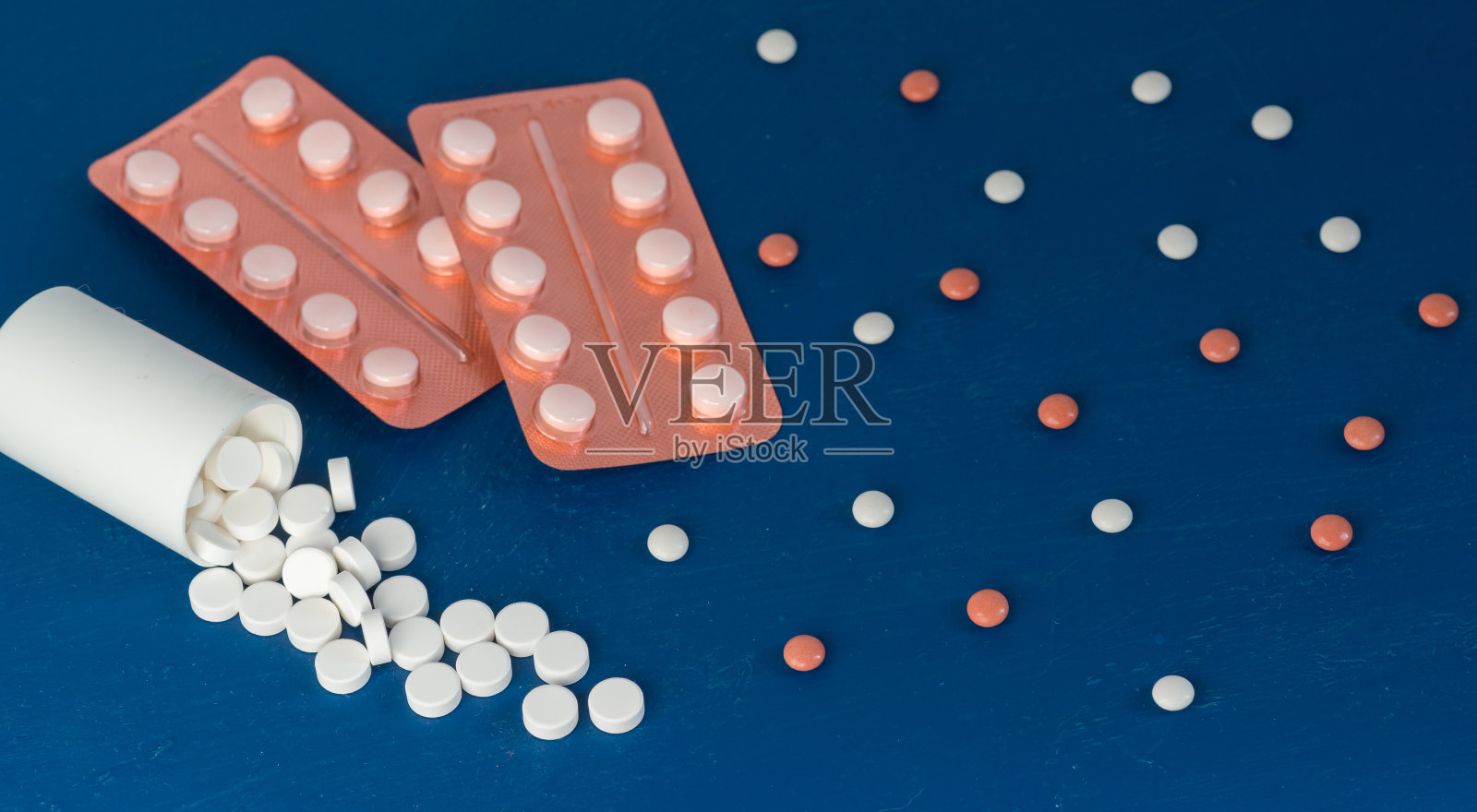 蓝色背景上的水泡中散落着白色和棕色的药片。治疗冠状病毒的药物。本空间照片摄影图片