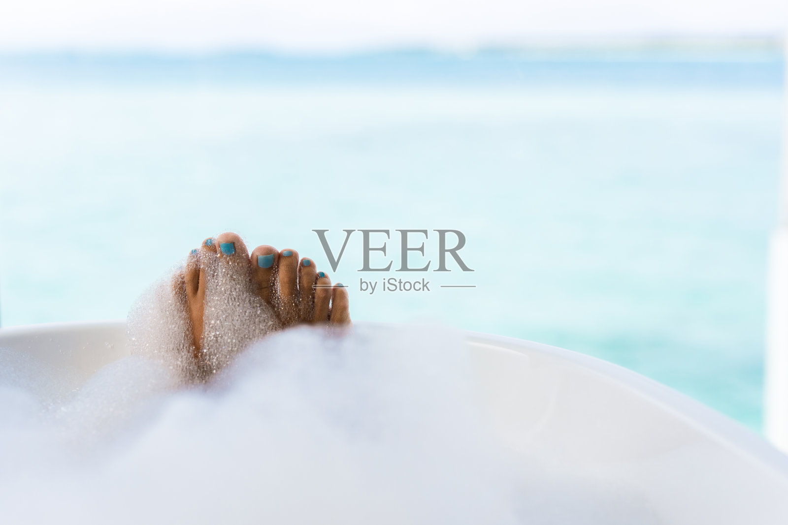 在泡沫浴中无法辨认的女人的脚的特写。照片摄影图片