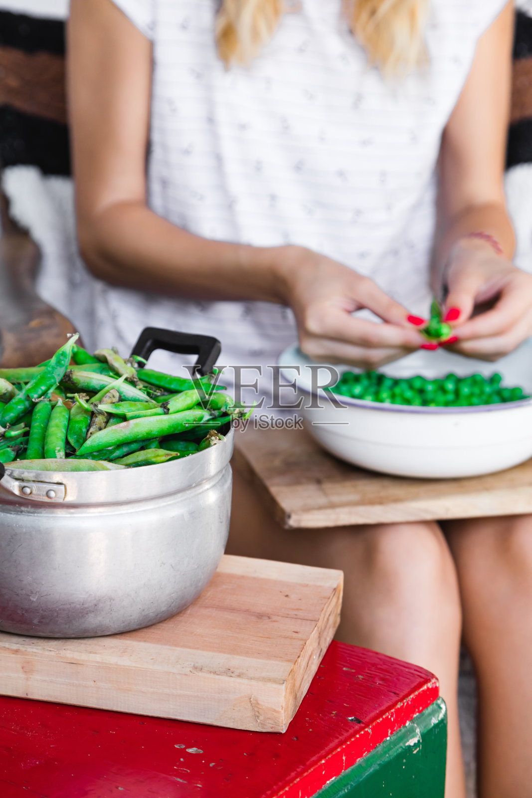 一名妇女正在准备新鲜的有机豌豆,并将其从壳中取出。照片摄影图片