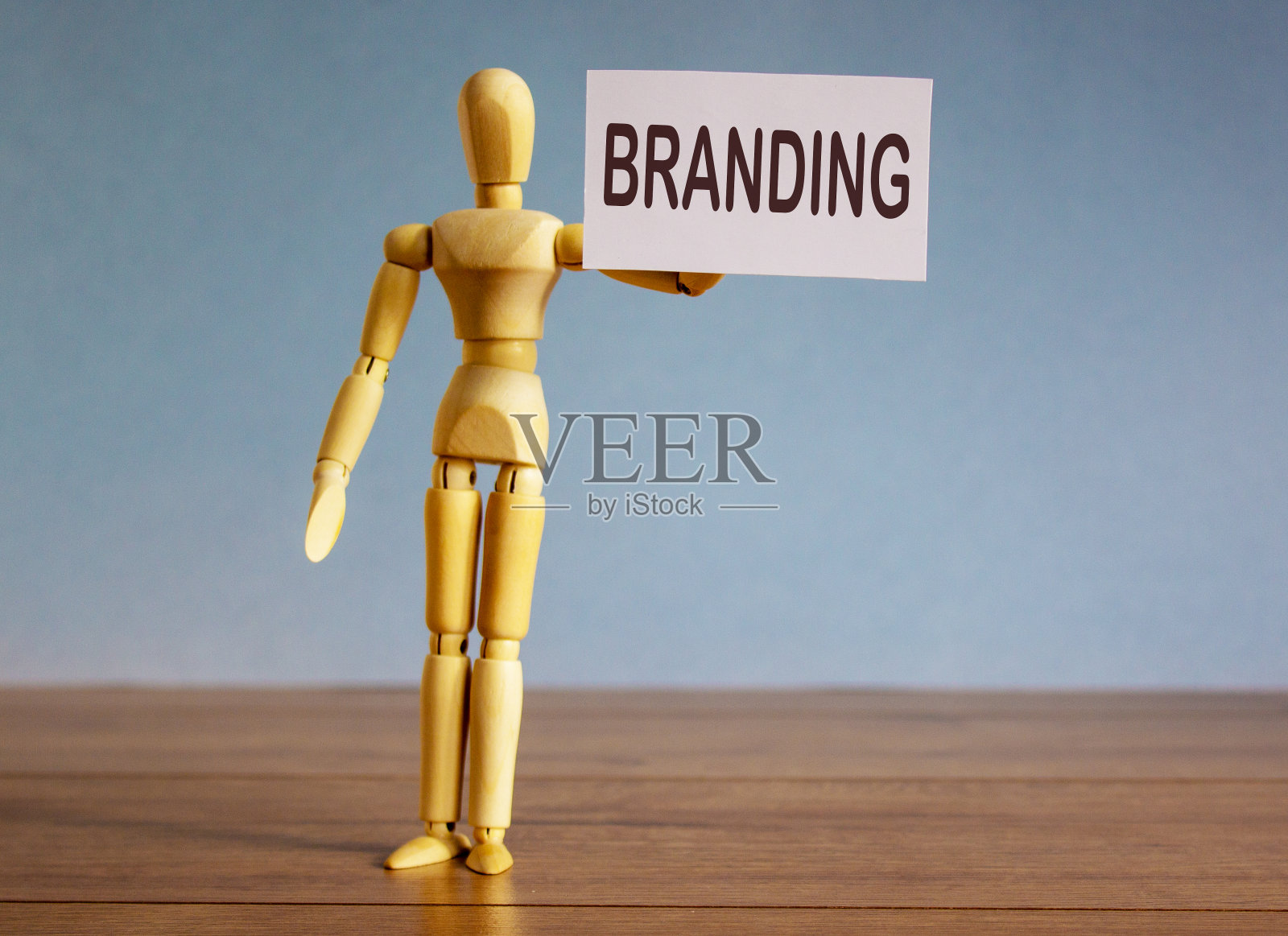 木制模型,一个男人拿着一块写着烙印的平板。照片摄影图片