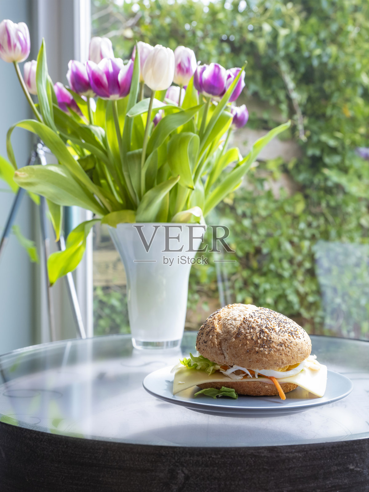 健康的早餐。意大利面包配生菜,芝士,火腿和鸡蛋,健康的三明治。背景花瓶中的郁金香,选择性聚焦照片摄影图片