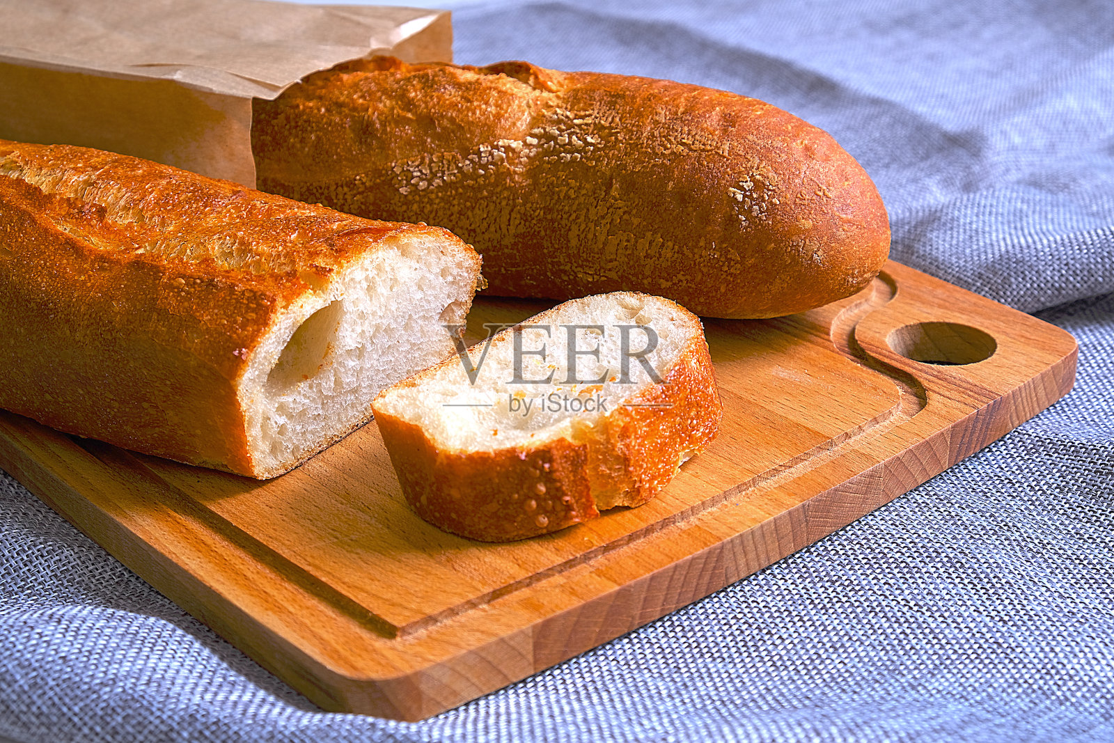 新鲜温暖的法棍面包,外皮酥脆。切片吃早餐。早上吃三明治。照片摄影图片