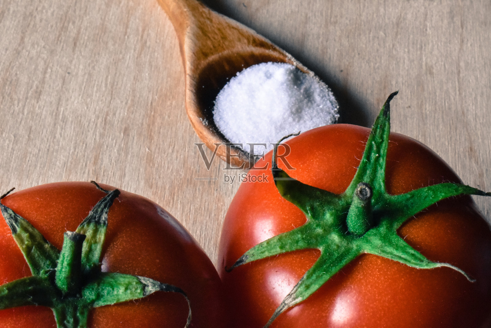 在桌子上用木勺舀两个西红柿和盐照片摄影图片