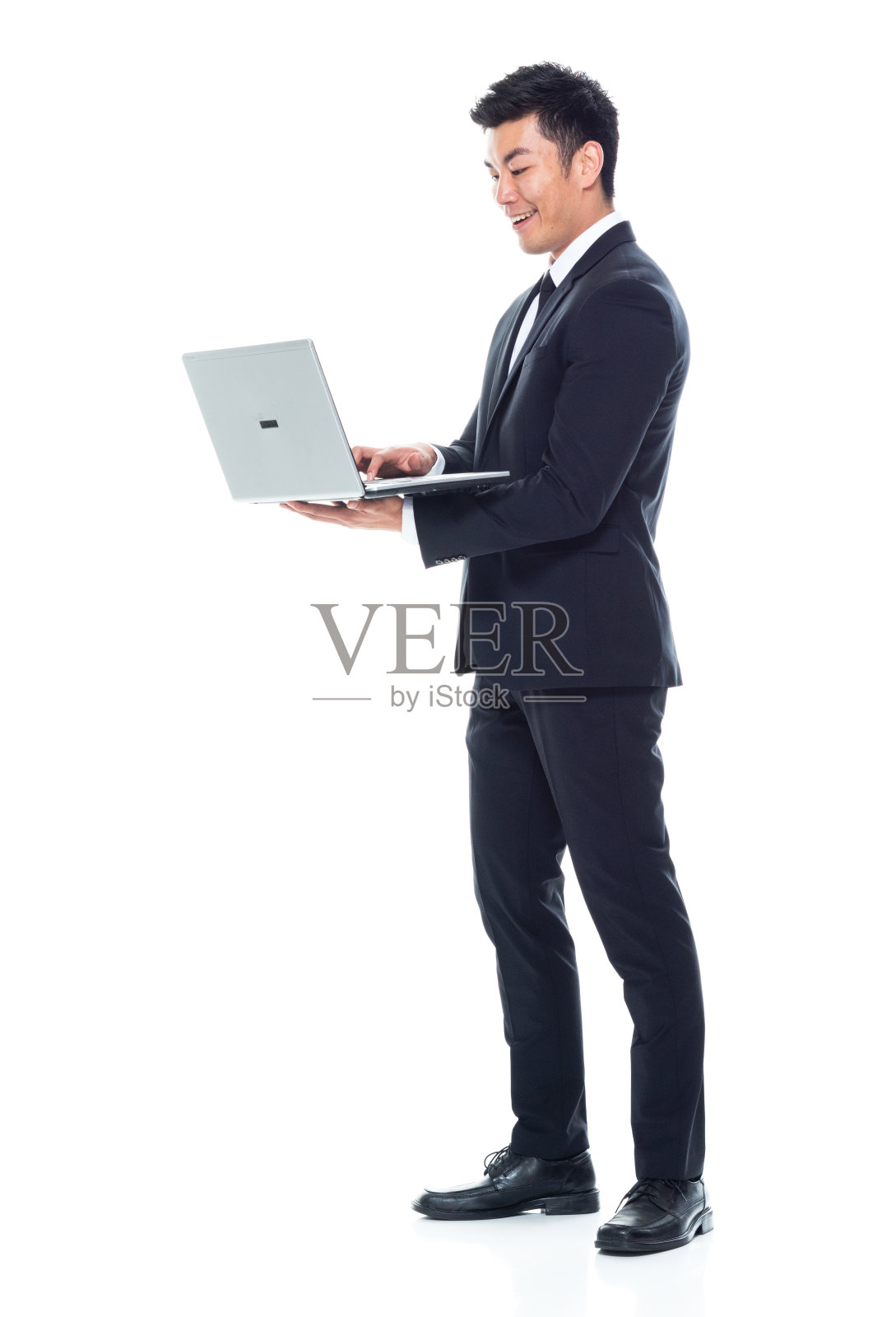 东亚裔男性经理站在白人背景前使用笔记本电脑照片摄影图片