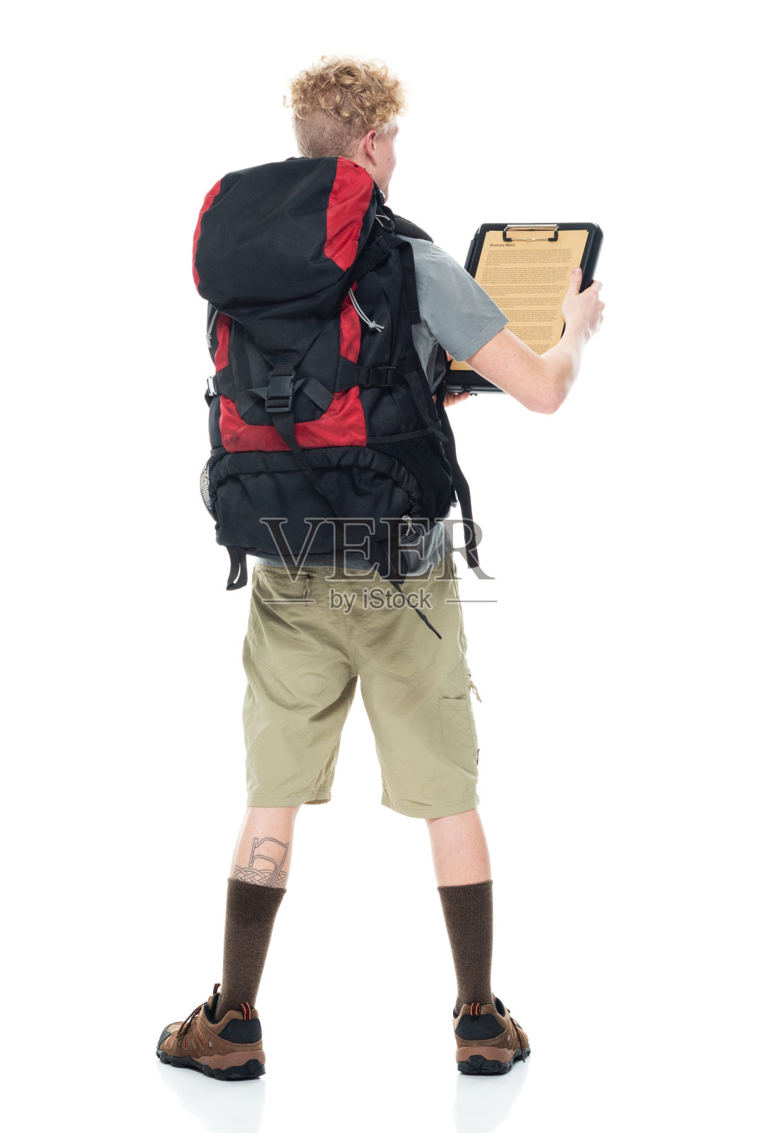 白人男性背包客在白色背景前徒步旅行,穿着背包和拿着文件照片摄影图片