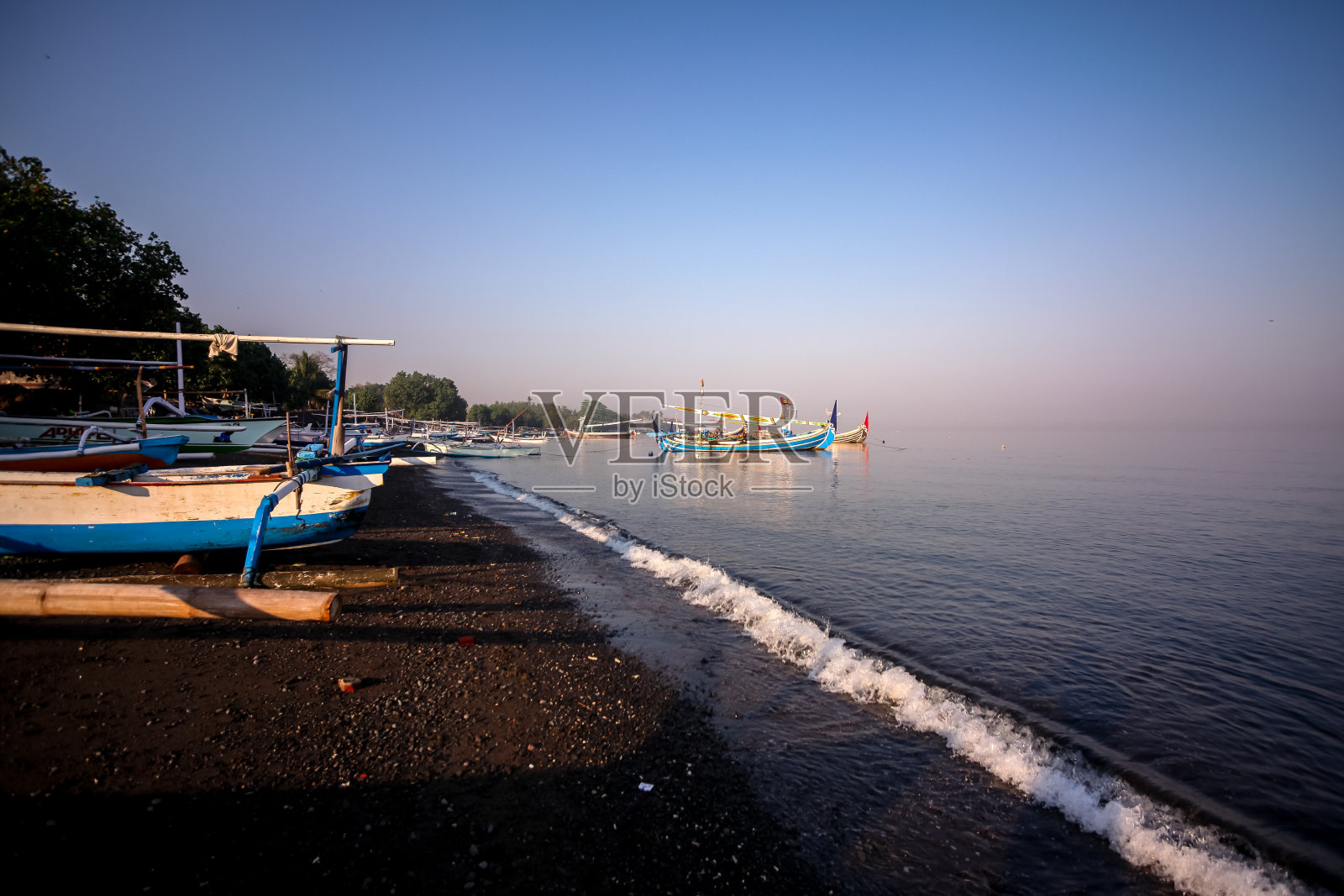 在印度尼西亚的巴厘岛北部,有船和火山黑沙的海滩全景照片摄影图片
