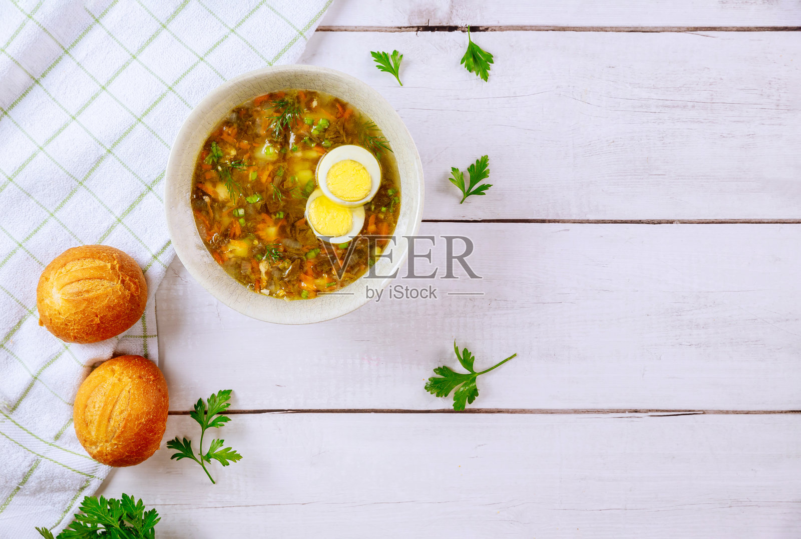 健康的酸模汤,鸡蛋和硬皮卷。照片摄影图片