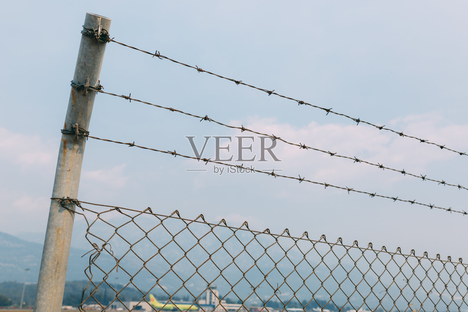 一个有刺铁丝网的篱笆顶着天空,一个有网奴隶的篱笆照片摄影图片