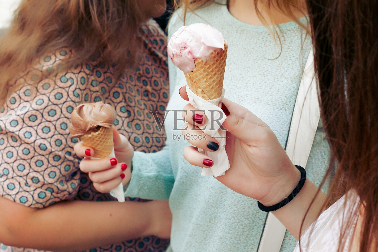 手里拿着冰淇淋。一群妇女拿着巧克力和粉红色的冰淇淋在手近距离,聚会和有乐趣的城市街道照片摄影图片