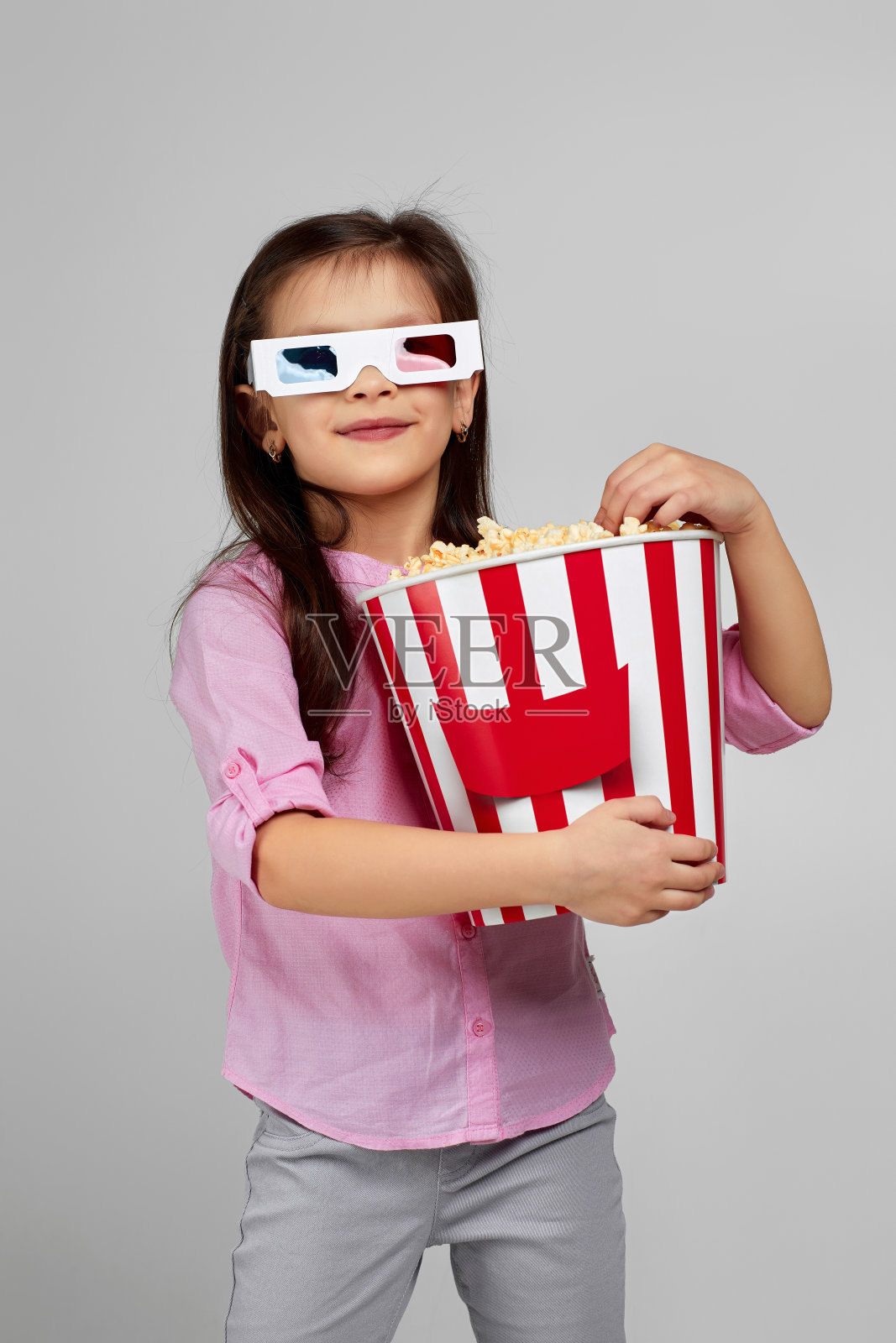 戴着红蓝色3d眼镜吃爆米花的小女孩照片摄影图片