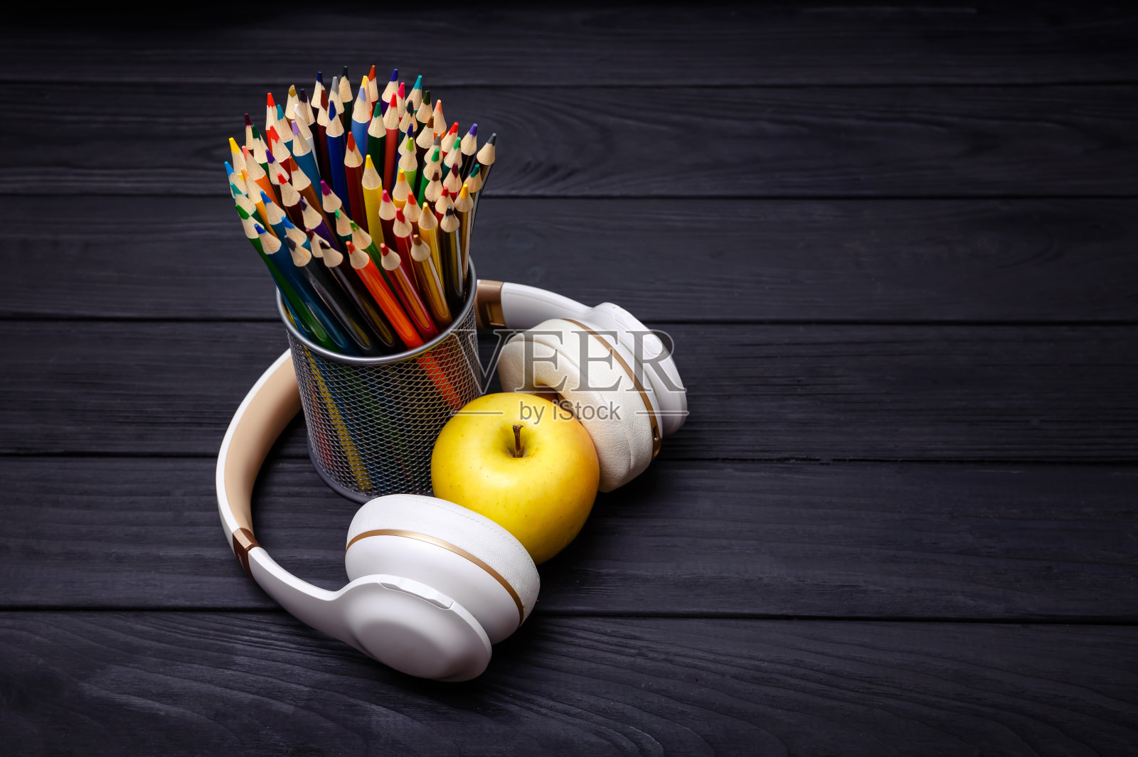 黑色木质背景上的彩色铅笔和耳机。工作场所照片摄影图片