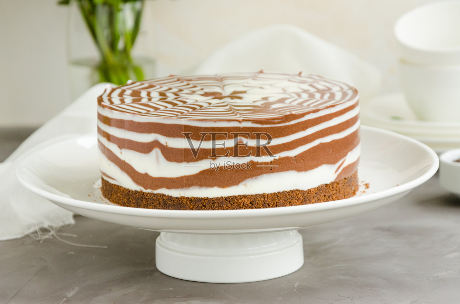 没有烤斑马大理石芝士蛋糕与香草和巧克力层的白色盘子在混凝土背景。水平方向。近距离照片摄影图片