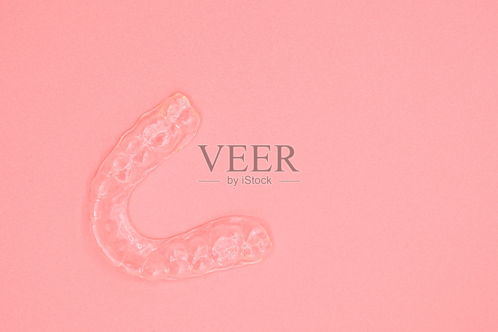 牙齿的塑料印模。矫正硅胶教练。用于矫正牙齿的移动矫正器,粉红色背景。照片摄影图片