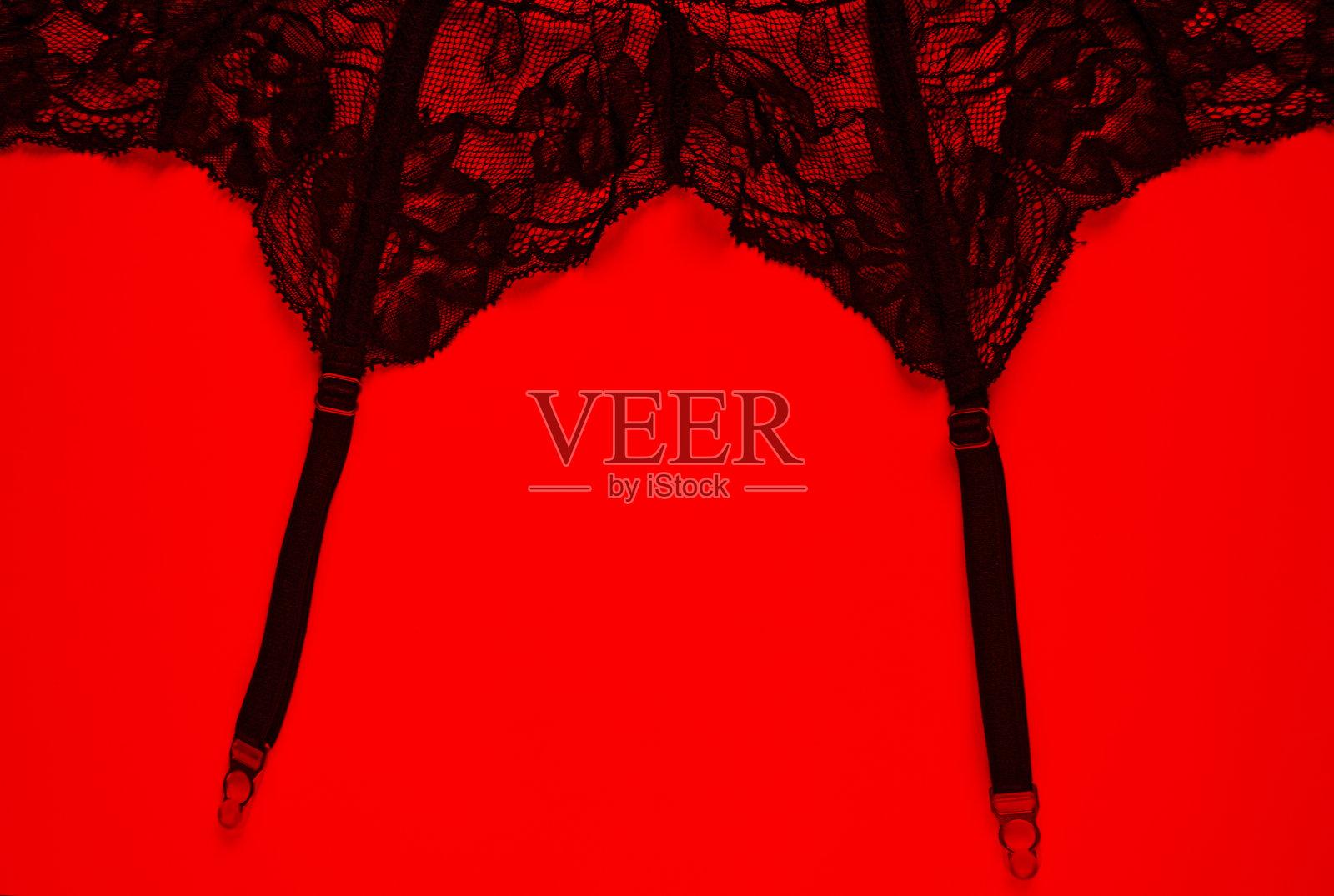 红色背景上的吊袜带。性感女性内衣与复制空间。性感内衣,黑色镂空腰带。激情和浪漫的主题。情人节!照片摄影图片
