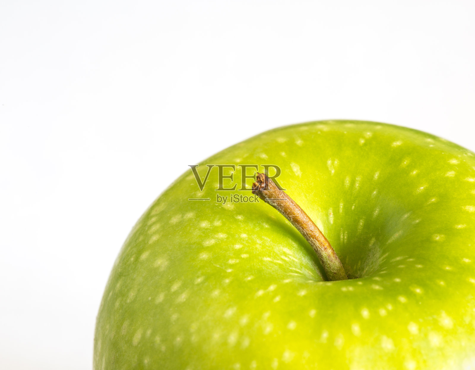 一个特写显示了一个在白色背景上打蜡的绿苹果的茎和细节照片摄影图片