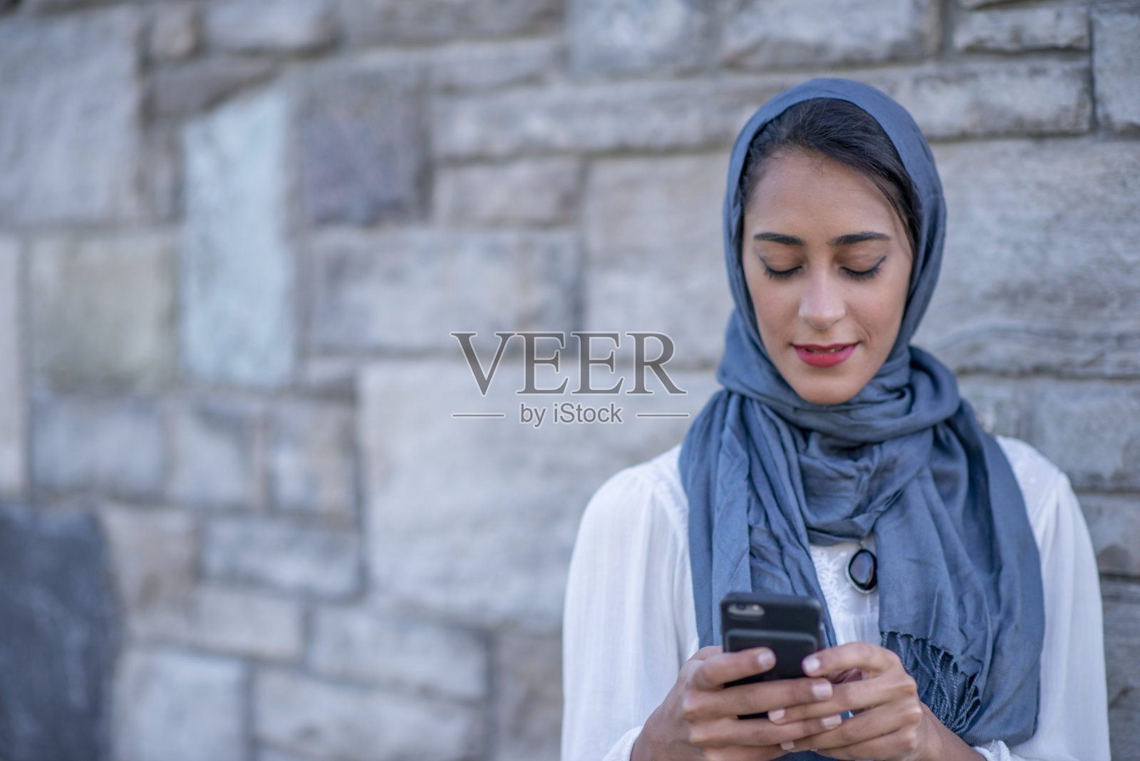 使用智能手机的年轻穆斯林女人照片摄影图片