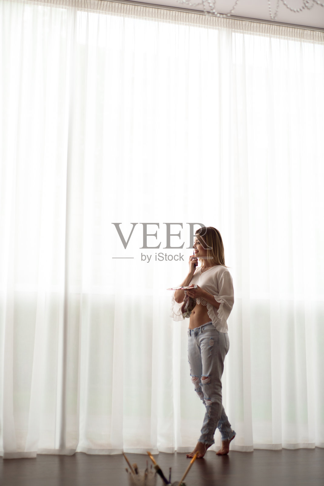 艺术、创意、工作和创意职业理念。女艺术家在窗前摆姿势,用油画或丙烯颜料作画照片摄影图片