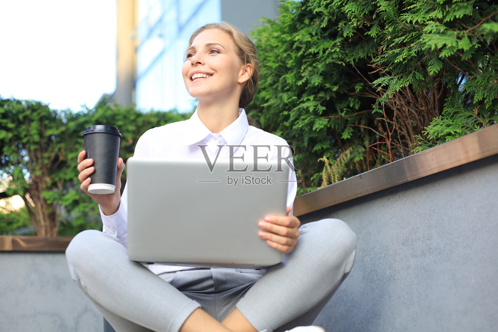 美丽的商务女性坐在商务中心附近,使用笔记本电脑。照片摄影图片