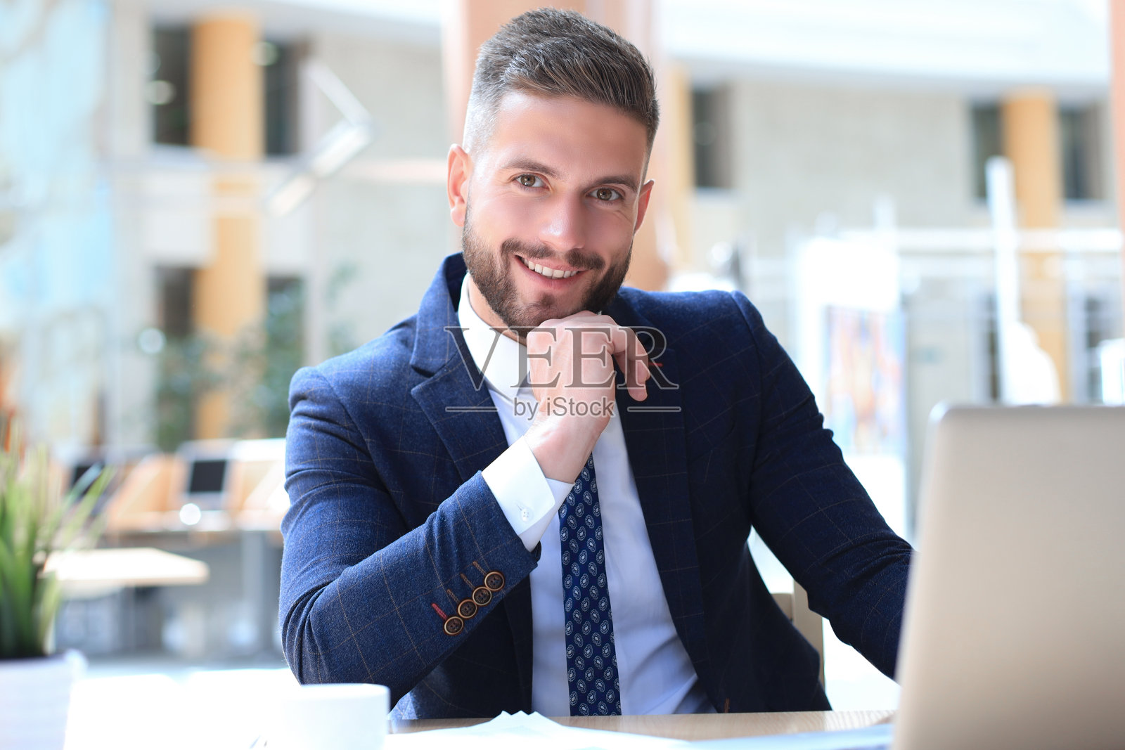 一个年轻人坐在办公室的办公桌前。照片摄影图片