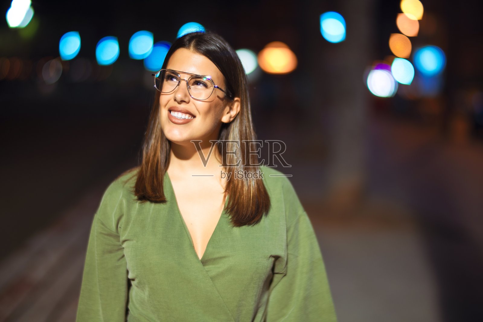 年轻美丽的姑娘微笑着快乐自信地走在步行街上,面带微笑地站在灯火散科的夜景周围照片摄影图片