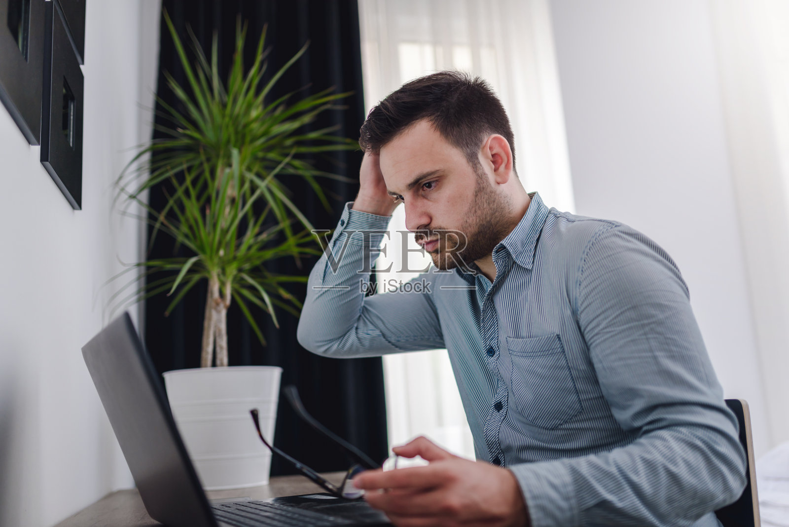 用笔记本电脑的男人,在家里工作。担心财政。照片摄影图片