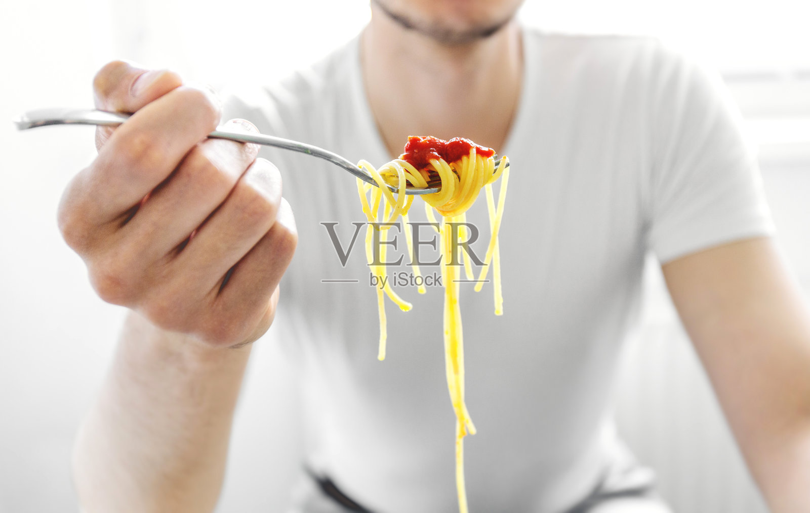 一个男人在吃美味的意大利面,配上番茄酱照片摄影图片