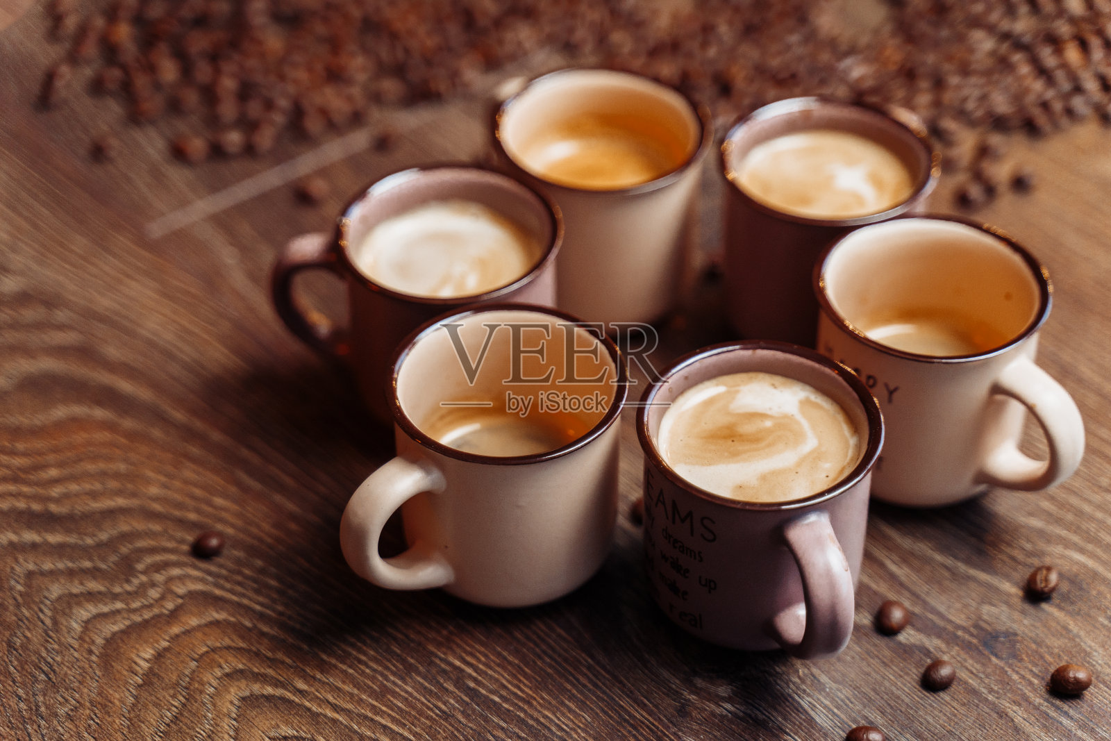 木质背景上的咖啡杯和咖啡豆。从以上观点。棕色的背景。关闭了。木质地板上放着咖啡杯,周围是烘豆照片摄影图片