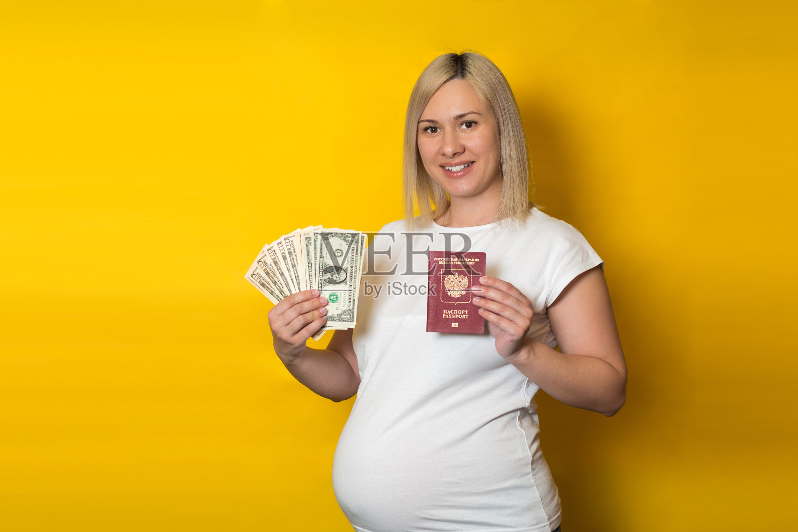 拿着护照和钱的孕妇。孕妇的福利,黄色背景照片摄影图片