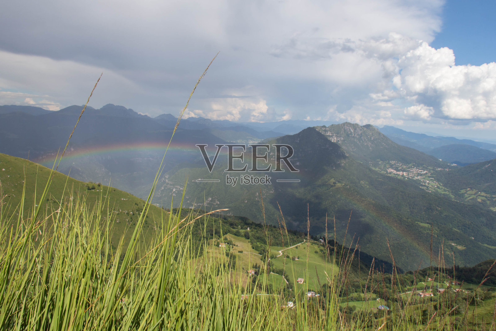 在一个阳光明媚的日子里,山峦上有彩虹,风景如画。照片摄影图片