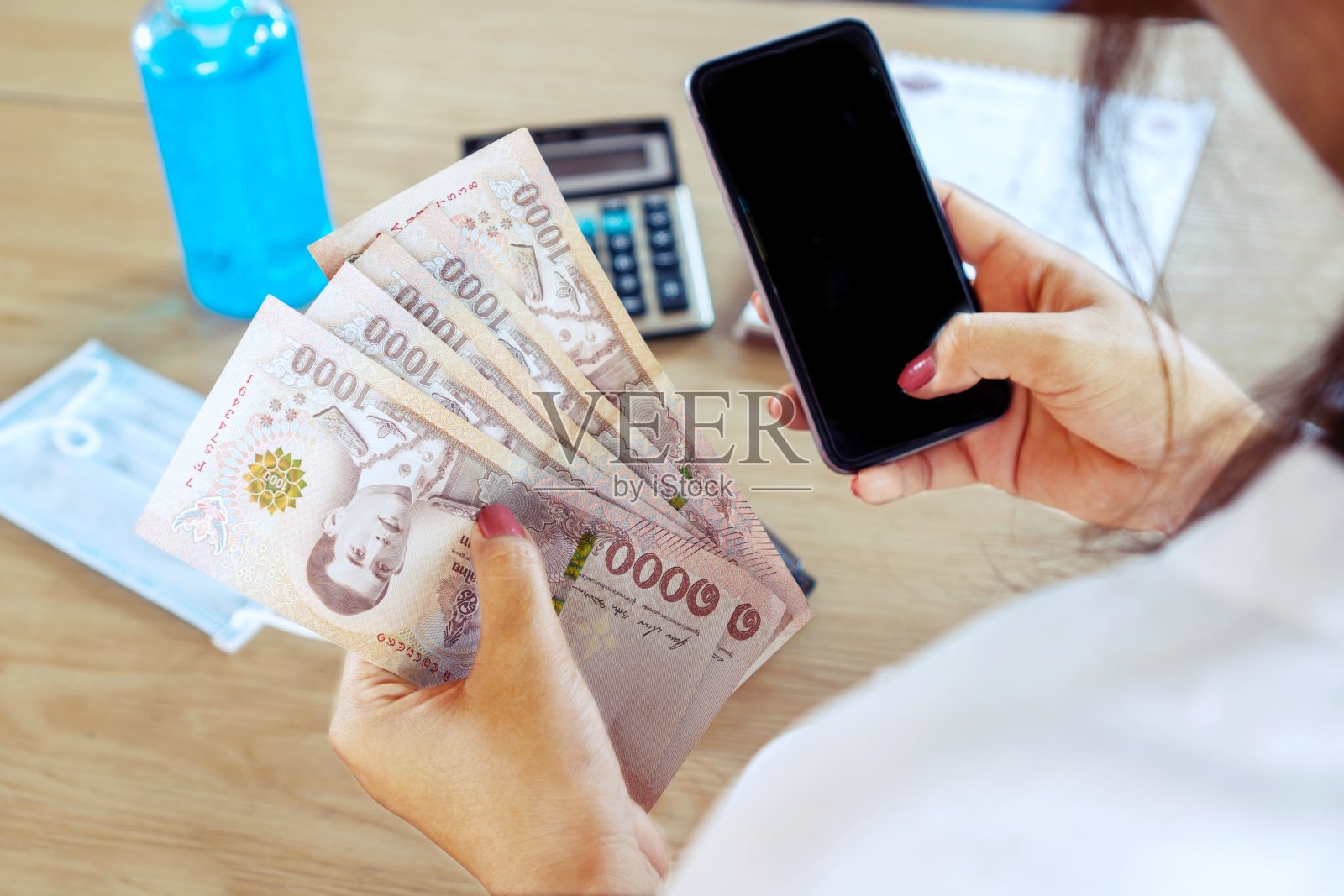手持智能手机的妇女和5000泰铢的泰国钞票,新冠肺炎债务帮助的概念或来自政府的现金补贴照片摄影图片