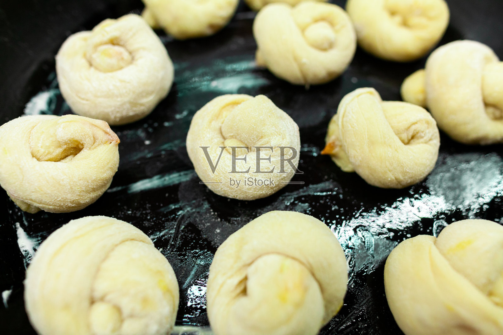 油乎乎的烤盘上放着自制的甜酵母面包照片摄影图片