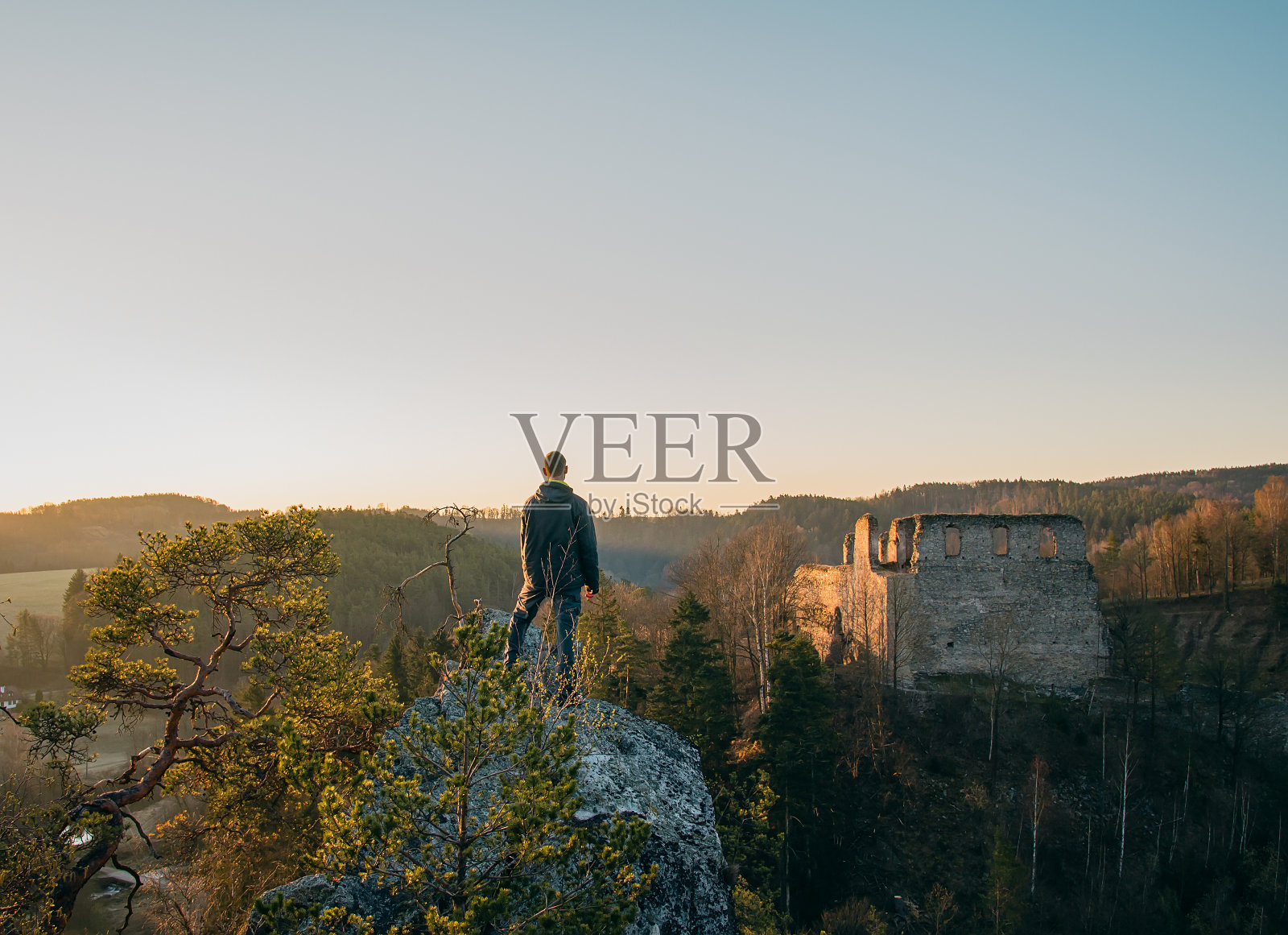 穿着夹克和裤子的年轻人站在那里想把迪夫西假面从岩石上毁了。捷克共和国照片摄影图片