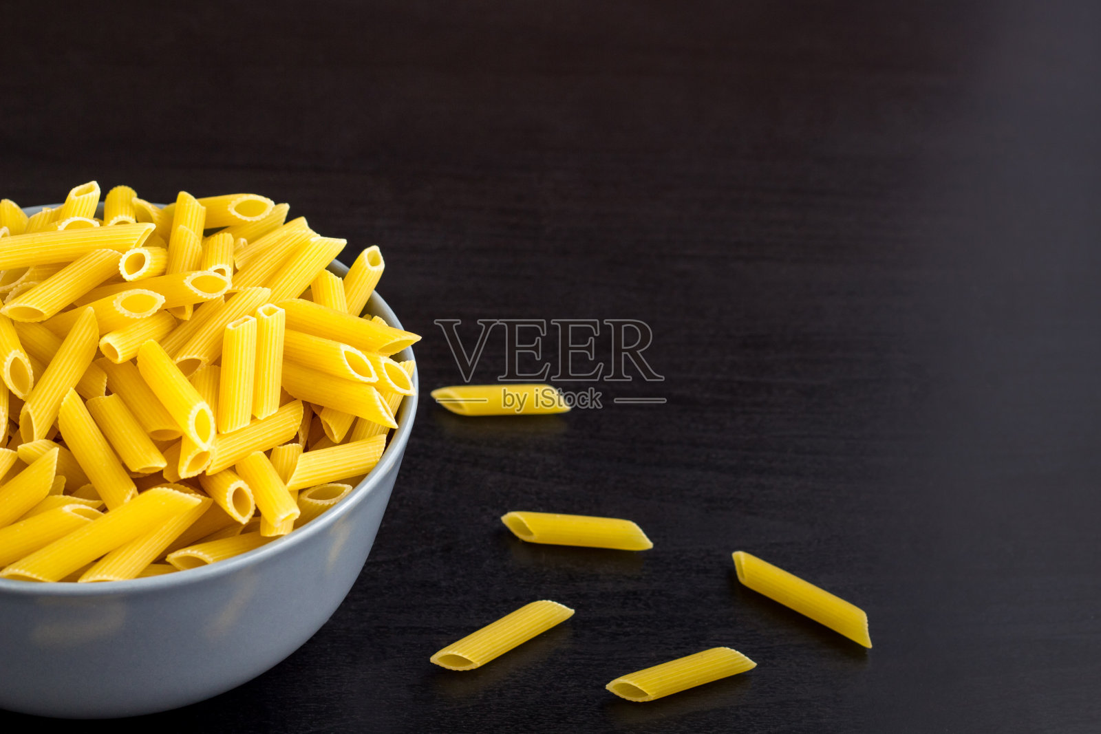 黑色背景与意大利生通心粉或意大利面碗与复制空间照片摄影图片
