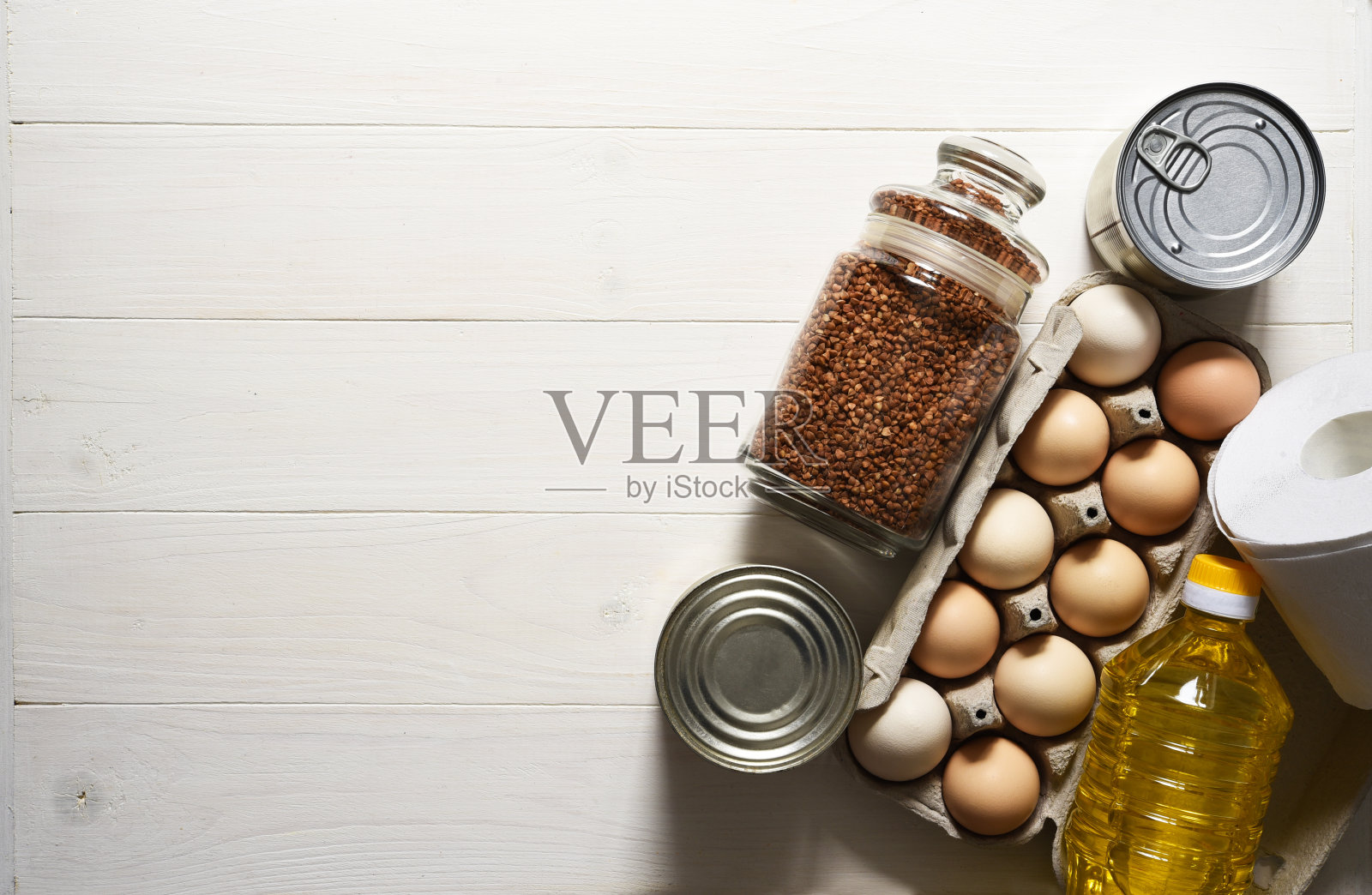 食物捐赠在一个白色的木制背景:油,荞麦,鸡蛋,罐头食品。坐在家里。隔离。食品交付。照片摄影图片