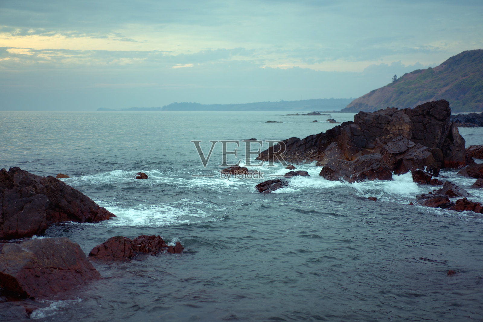岩石海滩风景。白色浪花溅在石头上。照片摄影图片