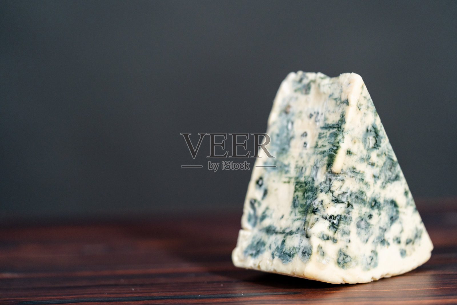 黑色木质背景上的大块楔形蓝纹奶酪。照片摄影图片