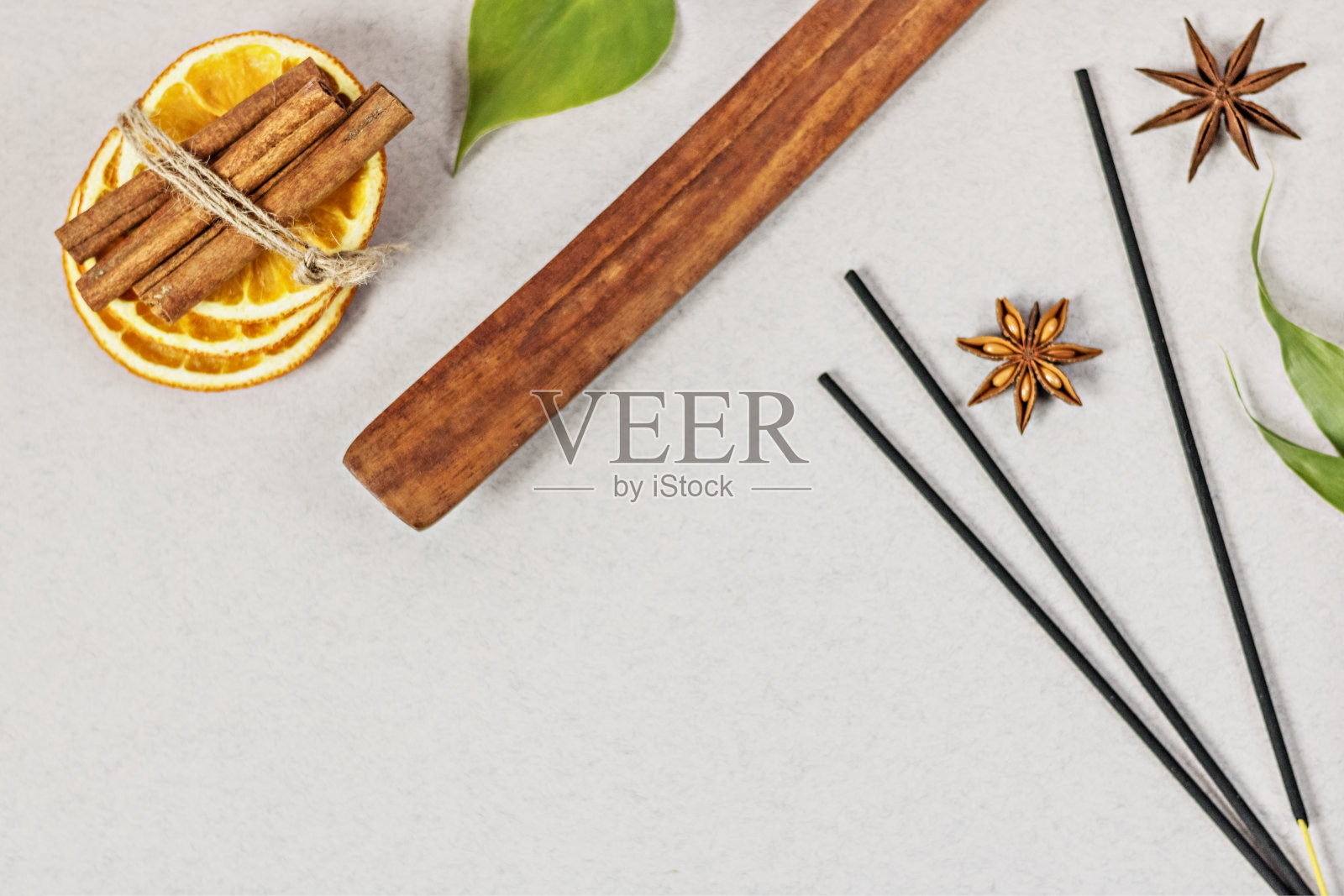 香与支架,切成橙色圆圈在木碗和八角,肉桂棒在灰色的背景。花和贝壳形状的蜡烛。芳香疗法。家庭spa的概念。照片摄影图片