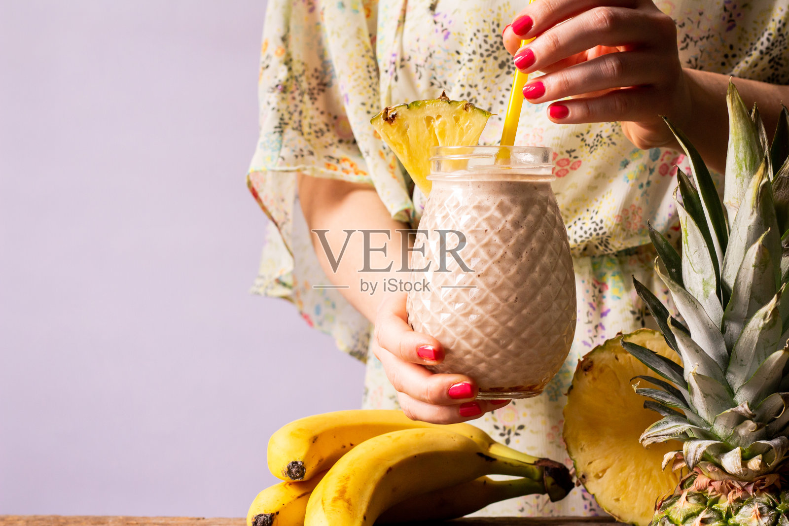 新鲜制作的冰沙,香蕉和菠萝在女人的手中。健康的早餐和零食,生活理念。夏天的点心。副本的空间。照片摄影图片