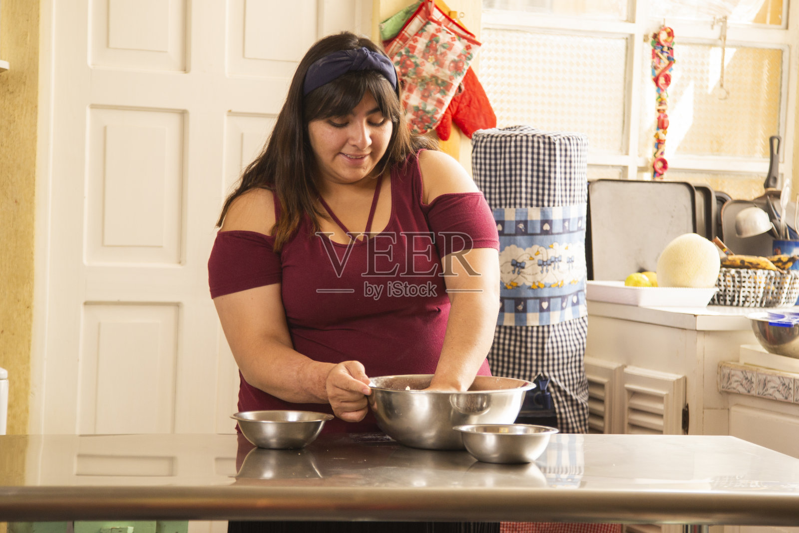 年轻的西班牙妇女在家里做饭-年轻妇女准备饼干-家庭食物照片摄影图片