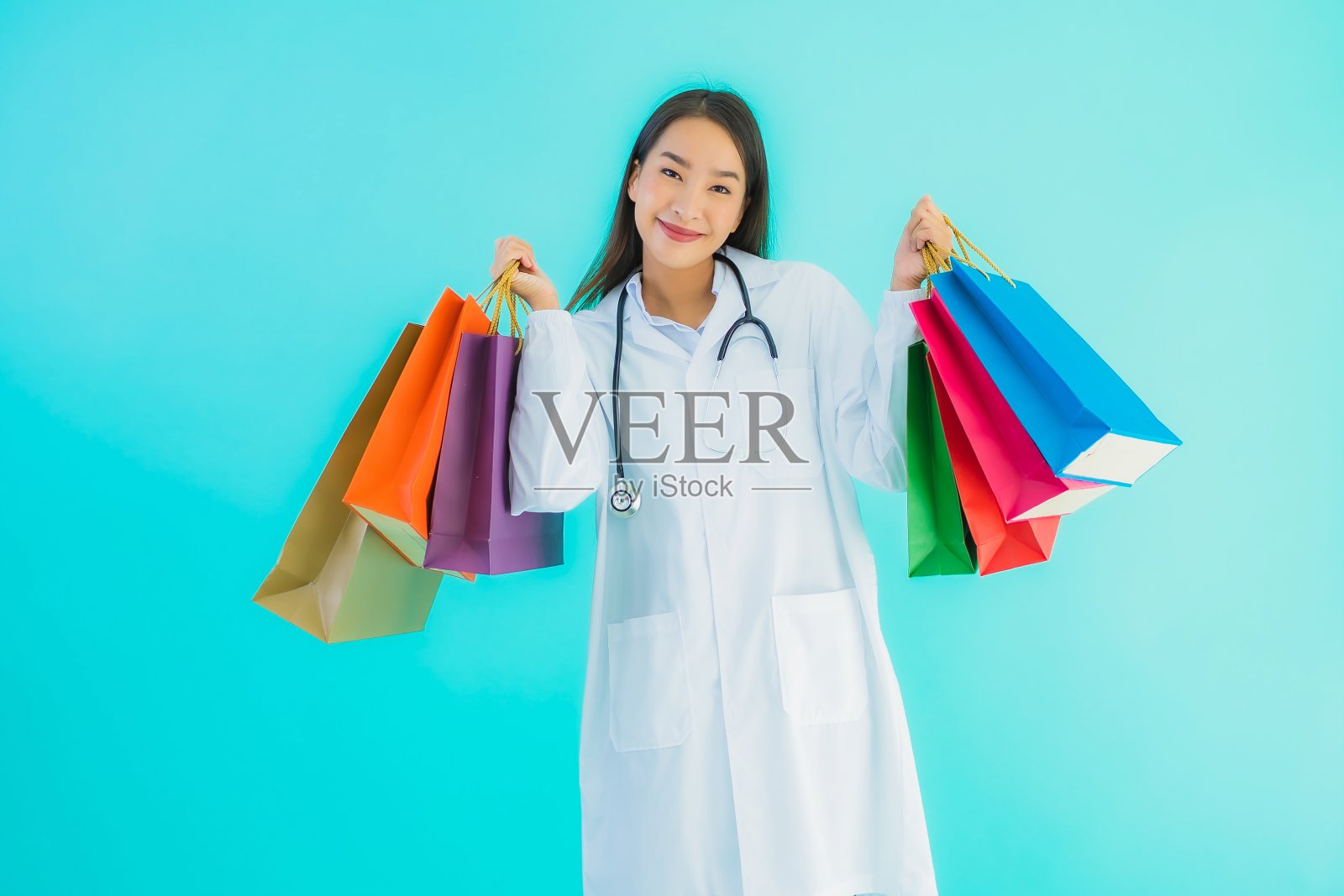 肖像美丽的年轻亚洲女医生与彩色购物袋照片摄影图片