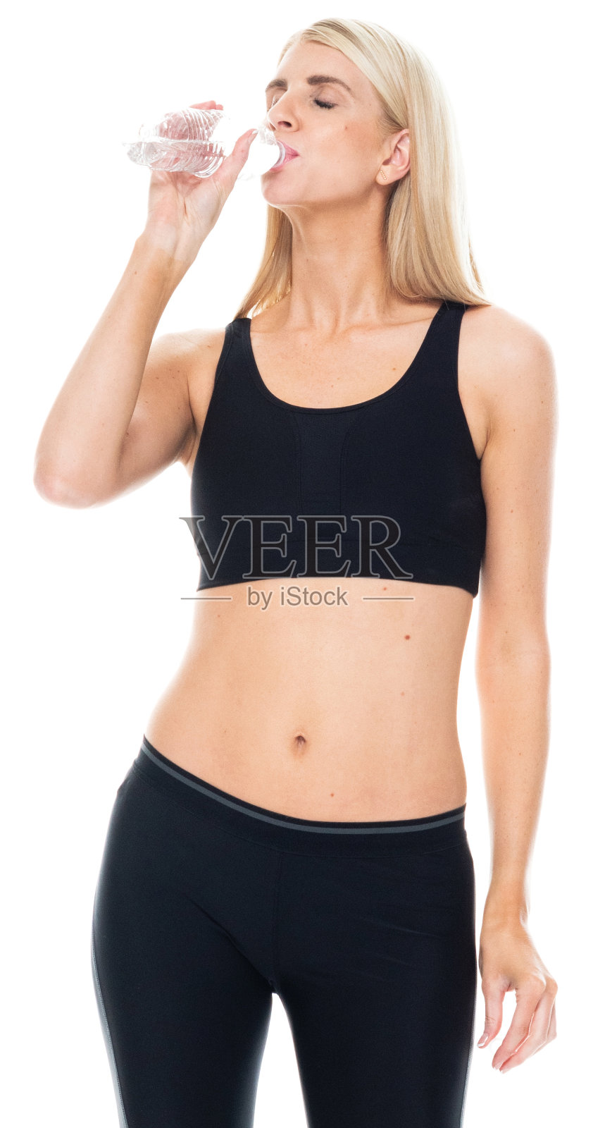 白人年轻女运动员穿着运动鞋,手持水瓶站在白色背景前照片摄影图片