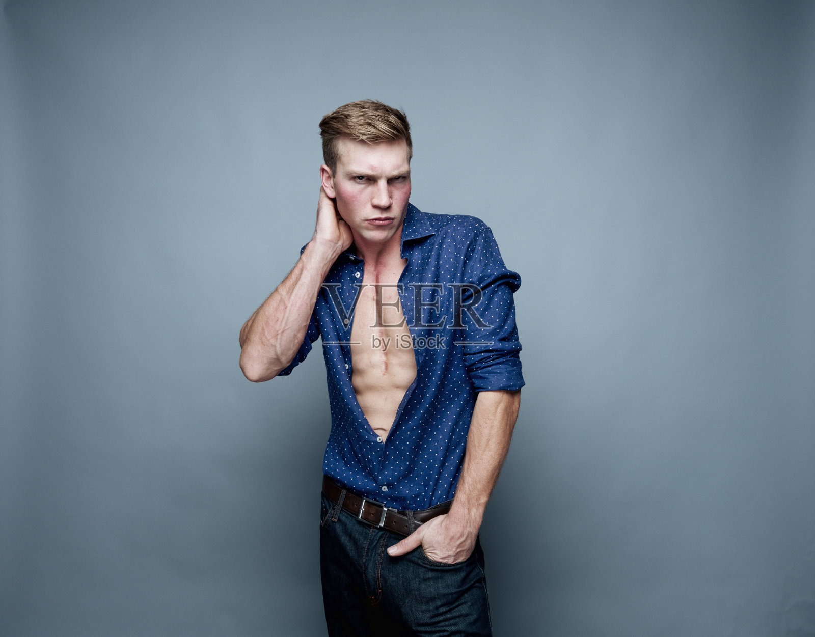 白人年轻男性脱衣舞娘在灰色背景穿着纽扣衬衫照片摄影图片