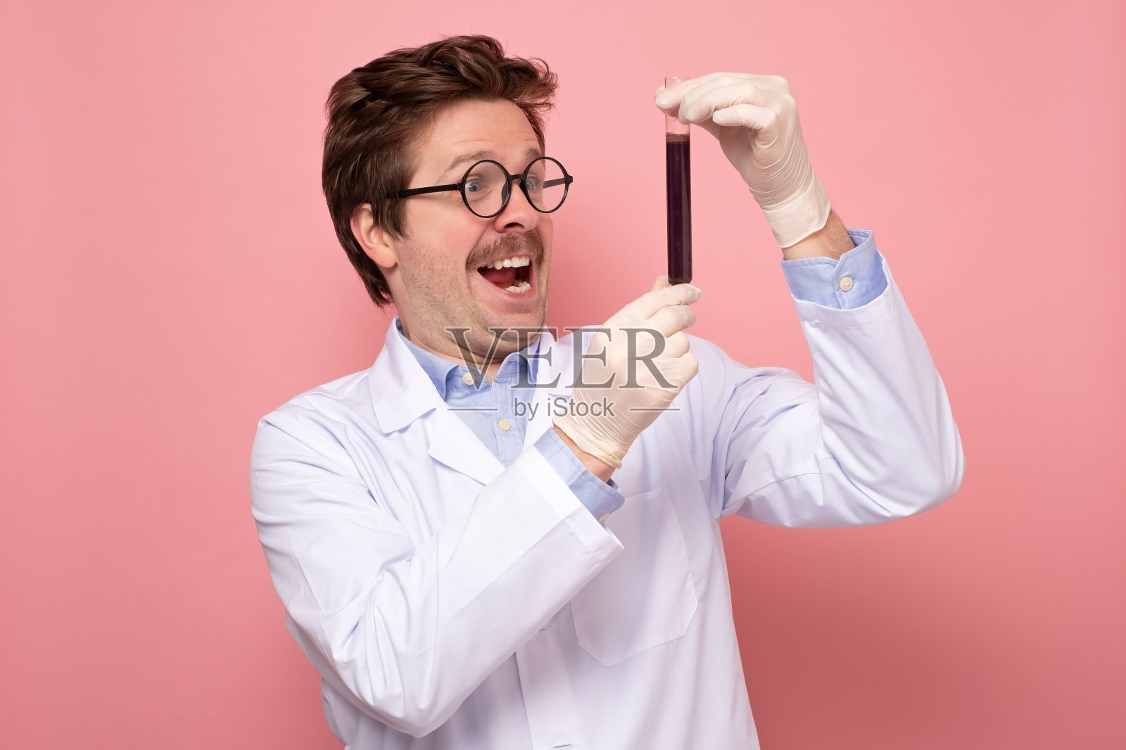 科学家拿着一个装有蓝色液体的玻璃管很高兴,他有了一个伟大的发现。照片摄影图片