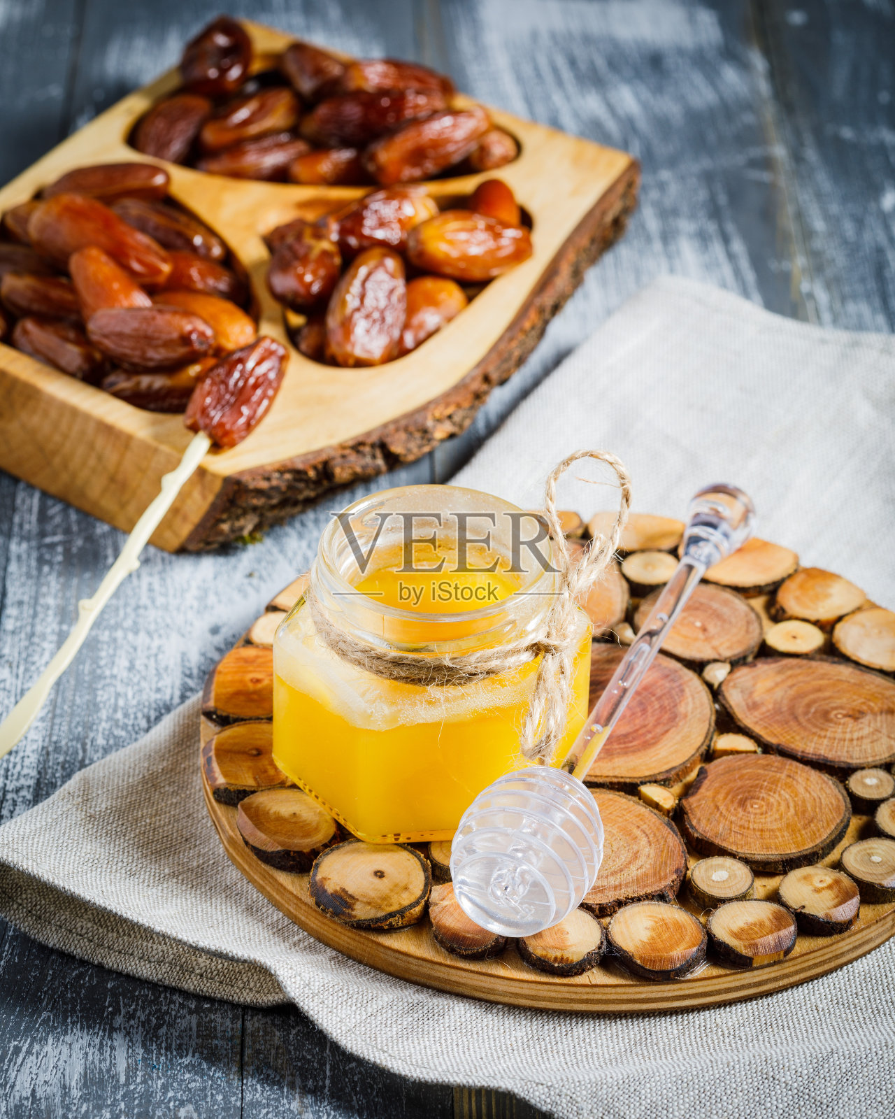 装有有机蜂蜜的罐子和木色背景的勺子照片摄影图片