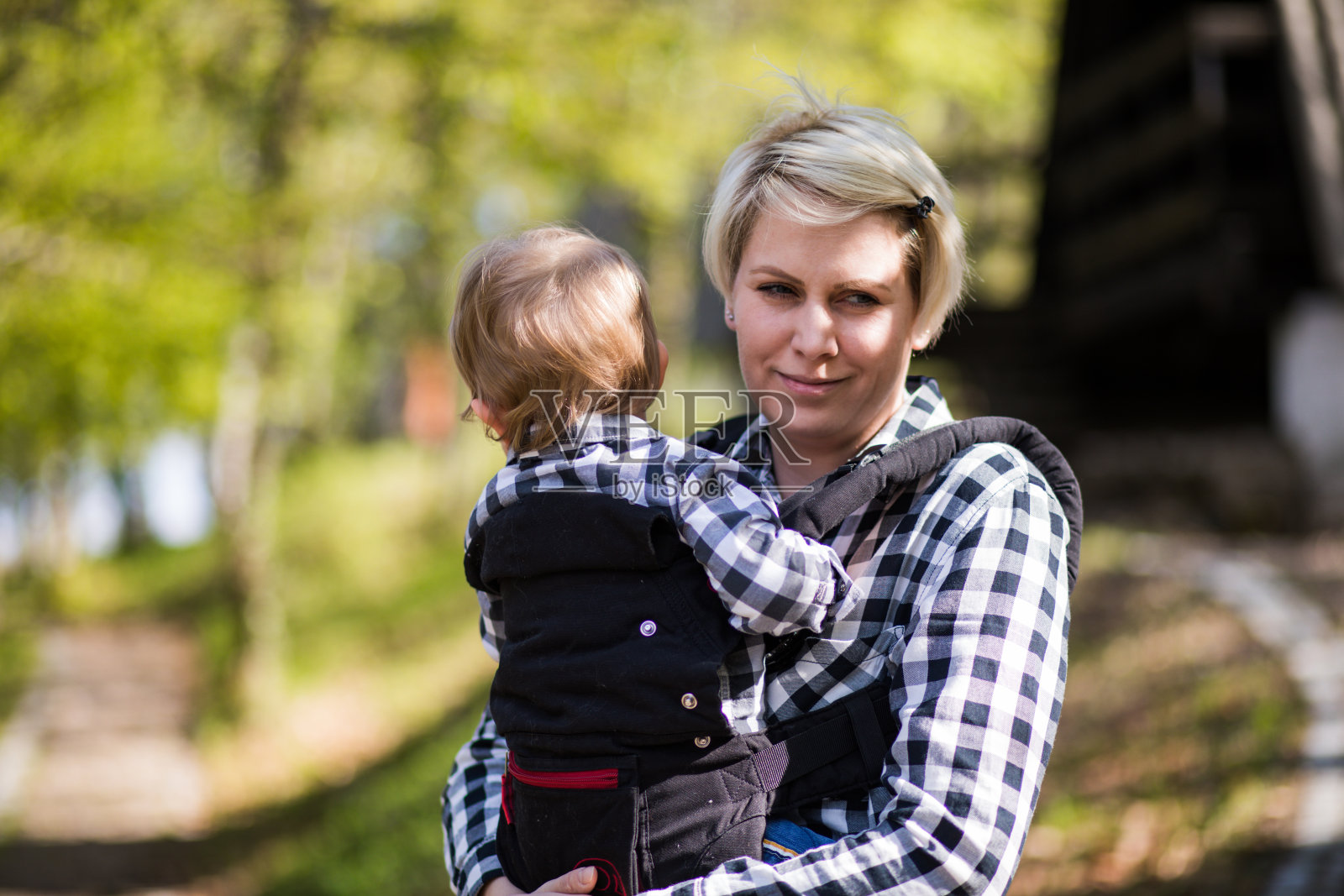 美丽快乐的年轻母亲与婴儿抱在公园。照片摄影图片