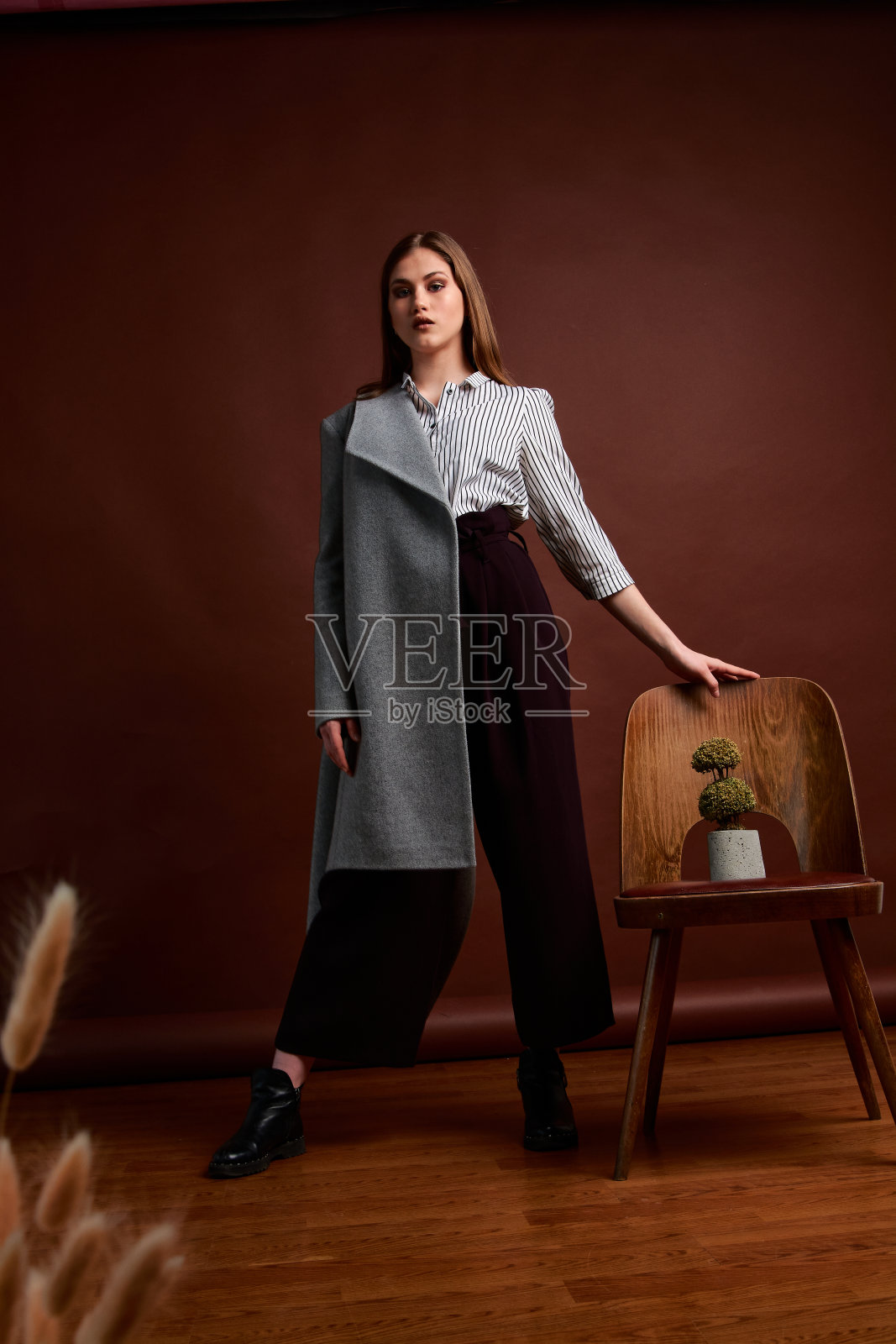 漂亮的年轻女性,穿着经典的套装,黑色的鞋子和灰色的外套。古董椅子。女人的衣服。照片摄影图片
